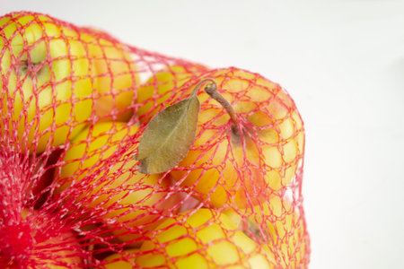 Apples in the shopping net. In the red grid are yellow apples. Mesh with apples on a white background. A grid for shopping with fruits.の写真素材