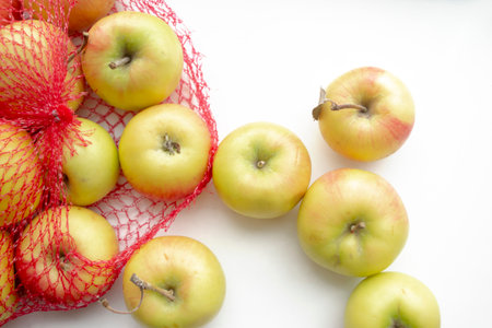 Apples in the shopping net. In the red grid are yellow apples. Mesh with apples on a white background. A ECO grid for shopping with fruits.の写真素材