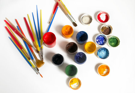 For artists, there are a lot of colored paints and brushes. Watercolor paints next to the brushes. Paints and brushes on a white background. Oil paints on the table.の写真素材