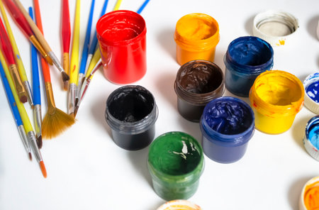 Watercolor paints next to the brushes. For artists, there are a lot of colored paints and brushes. Paints and brushes on a white background. Oil paints on the table.の写真素材