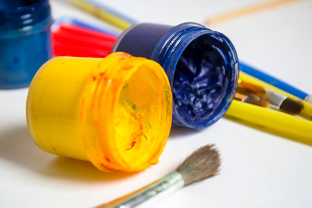 Yellow and blue jars of paint with tassels. yellow-blue paints on a white table with tassels. Watercolor paints of the symbol of the flag of Ukraine.の写真素材