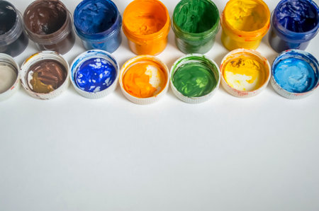Jars of watercolor paint stand in a row. Color watercolor with open lids on a white background. A number of watercolors.の写真素材