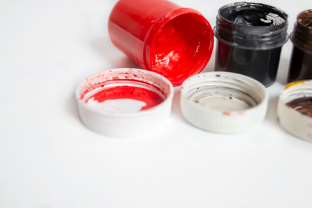Red watercolor next to black. jars with red and black watercolors on a white background. Colored paints on the table.の写真素材