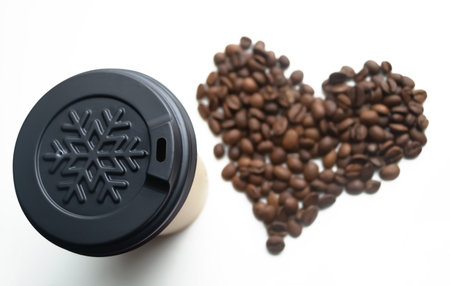 A winter cup on a white background, next to a heart of coffee beans. Coffee beans lined with a heart next to a paper cup. The love of coffee is heart and cup.の写真素材