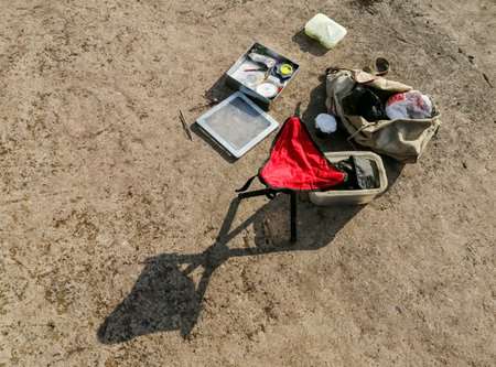Fishing accessories on the concrete floor. Outdoor fishing equipment has been laid out. Preparation for fishing - tackle and red chair.の写真素材