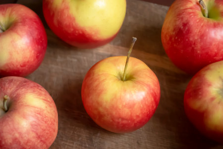 Red apples lie on a wooden board. A lot of champion apples. Large red apples with yellow stripes. Whole apples on the table.の写真素材