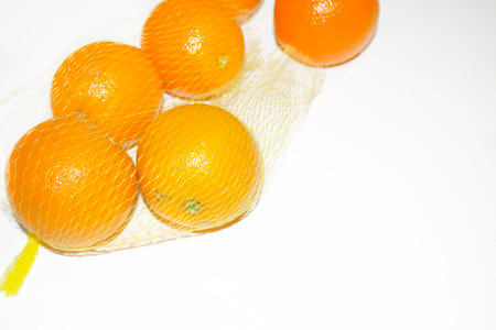 Oranges in a net on a white table. Eco shopping - fruit net. Healthy citrus fruits - orange oranges.の写真素材