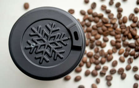 A cup of paper with a fish on a white background among the grains of the horse. Plastic cover about a snowflake on a coffee cup. winter cup among coffee beans.の写真素材