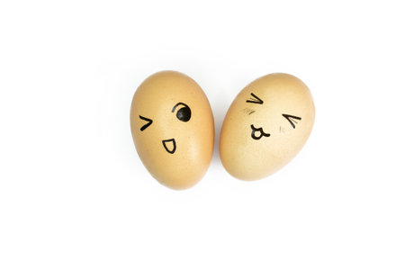 Two yellow eggs with painted emoticons on a white background. Eggs with smiles and eyes on white. Eggs with a face. Smiley on eggs.の写真素材