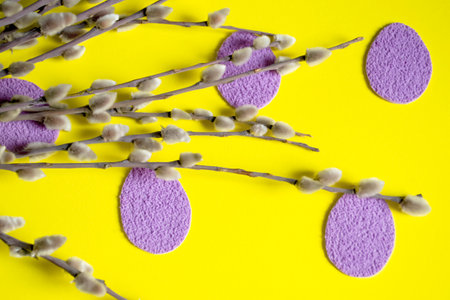 On a yellow background lie willow branches and purple paper eggs. composition at Easter - paper eggs with your own hands. Handicrafts for Easter from paper.の写真素材