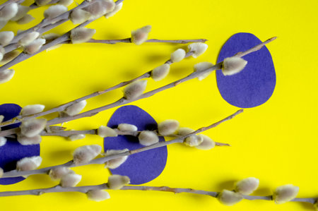 On a yellow background lie willow branches and blue eggs carved out of paper. Composition for Easter with your own hands. Crafts for Easter for children - paper eggs.の写真素材