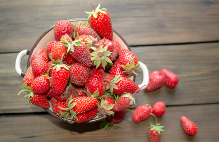 Fresh spring berries - strawberries from the garden in the plate and on the table. Strawberries from the garden in a plate. In a deep plate are dirty strawberries with green tails.の写真素材