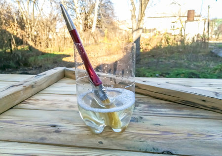 construction brush in a glass with paint solvent. A brush in the water. The used brush is cleaned in a transparent jar with solvent.の写真素材