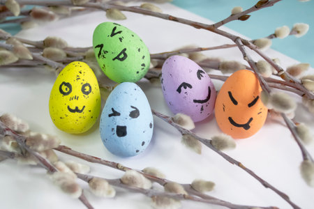 Festive Easter eggs on a white background among the branches of the willow. Eggs with emoji. emoticons on Easter eggs. Colored eggs with willow - Easter composition.の写真素材