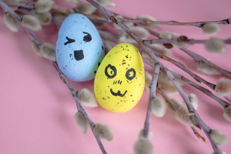 Festive Easter eggs on a pink background among the branches of the willow. Eggs with emoji. emoticons on Easter eggs. Colored eggs with willow - Easter composition.の写真素材
