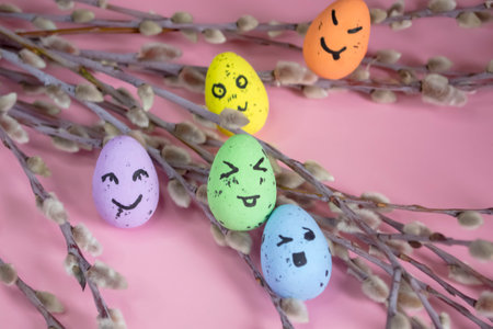 Festive Easter eggs on a pink background among the branches of the willow. Eggs with emoji. emoticons on Easter eggs. Colored eggs with willow - Easter composition.の写真素材
