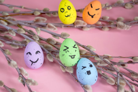 Festive Easter eggs on a pink background among the branches of the willow. Eggs with emoji. emoticons on Easter eggs. Colored eggs with willow - Easter composition.の写真素材