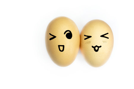 Two yellow eggs with painted emoticons on a white background. Eggs with smiles and eyes on white. Eggs with a face. Smiley on eggs.の写真素材