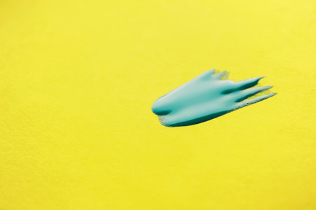 A spot of blue varnish on a yellow background. On a yellow background is blue nail polish.の写真素材
