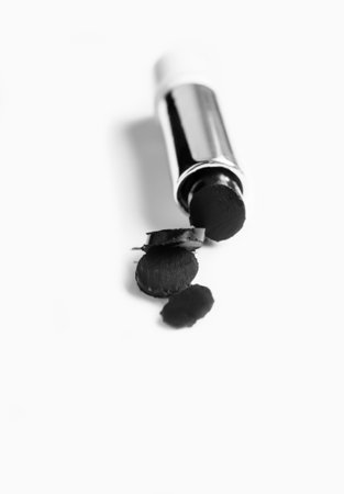 Black lipstick on a white background. the lipstick is cut. pieces of lipstick black on a white background. fashionable makeup colors.の写真素材