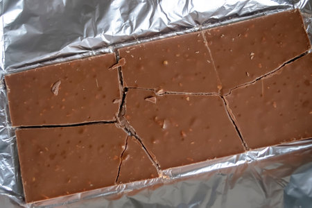 On the aluminum foil is a chocolate bar. Chocolate foil. pieces of broken chocolate. Milk chocolate is a broken bar.の写真素材