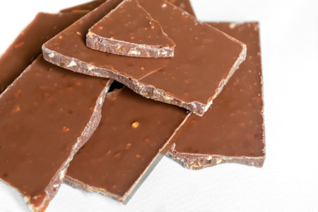 Pieces of broken chocolate on a white background. A broken chocolate bar is insulated. Delicious dessert chocolate.の写真素材