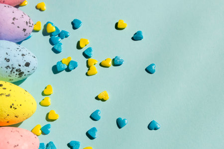 Next to the Easter eggs lies many yellow and blue hearts to decorate the pasoks. Decorations for the Easter holiday - colored eggs and powder in the form of hearts.の写真素材