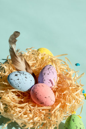 In the nested are Easter eggs and a bird feather. On a blue background is a nest with eggs for Easter. Quail eggs are painted with different colors.の写真素材