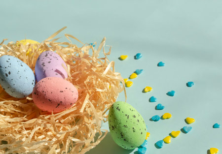 On a blue background lies a nest with Easter eggs, and next to yellow and blue hearts. Decorations for Easter. Delicious quail eggs layer coloring for Easter in the nest.の写真素材