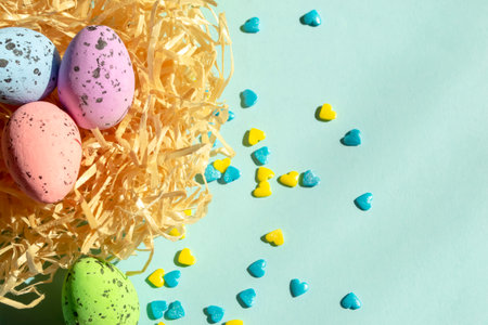 On a blue background lies a nest with Easter eggs, and next to yellow and blue hearts. Delicious quail eggs layer coloring for Easter in the nest. Decorations for Easter.の写真素材