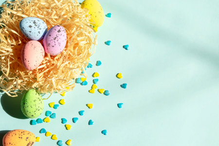 On a blue background lies a nest with Easter eggs, and next to yellow and blue hearts. Decorations for Easter. Delicious quail eggs layer coloring for Easter in the nest.の写真素材