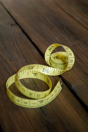 Measuring tape in yellow color. A yellow meter lies on a wooden table.の写真素材