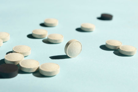 Lots of white and black pills on a blue background. Preparations for health and beauty - black and white pills. the pills lie chaotically.の写真素材
