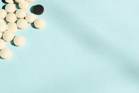 lots of white and black pills on a blue background. a handful of pills lie on a slide. tablets for treatment. health and beauty vitamins.の写真素材
