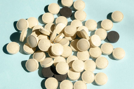 lots of white and black pills on a blue background. a handful of pills lie on a slide. tablets for treatment. health and beauty vitamins.の写真素材