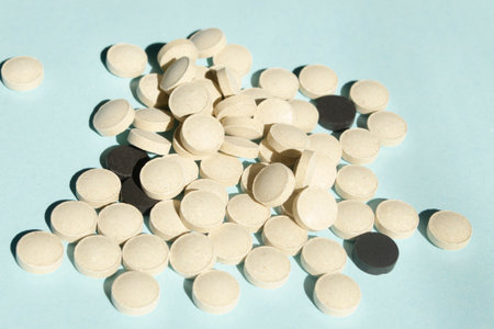 lots of white and black pills on a blue background. health and beauty vitamins. a handful of pills lie on a slide. tablets for treatment.の写真素材