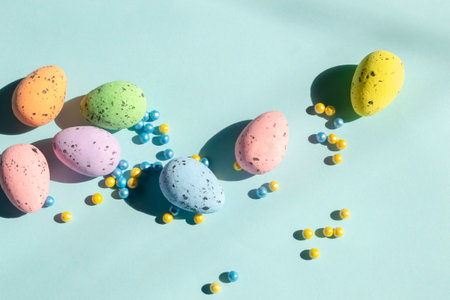 On a blue background lie Easter eggs and colored powder on paski. yellow and blue beads next to colored easter eggs.の写真素材