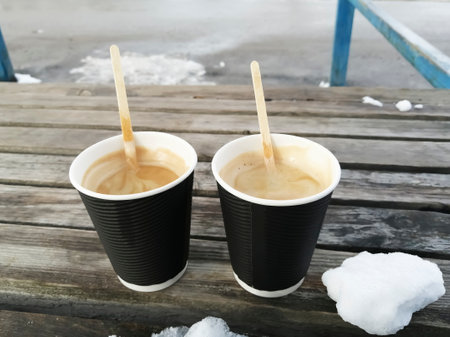 Two cups of coffee. On a wooden bench are two cups of Americano. black paper cups with hot coffee in winter.の写真素材