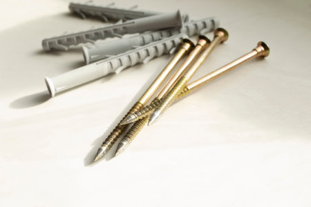 Dowels and screws on a light background. construction devices. On the dirty, white table are yellow screws and gray dowels.の写真素材