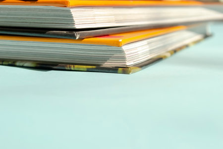 Books with a bright orange cover. The bright cover of the books stands out against a light blue background. On a blue background lies a stack of books.の写真素材