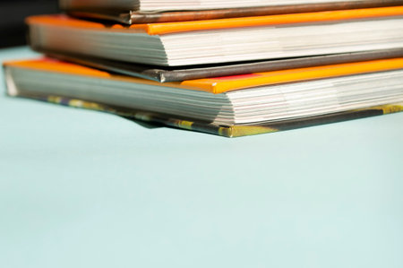 Books with a bright orange cover. On a blue background lies a stack of books. The bright cover of the books stands out against a light blue background.の写真素材