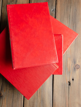 Books with a red cover on a wooden table. On a wooden background lies several books with a red cover. Textbooks for school and college.の写真素材