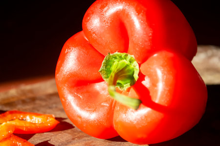 Red pepper on a wooden board. Bright, healthy vegetables. A constrate photo of a bell pepper with a red skin on a wooden board in the dark.の写真素材