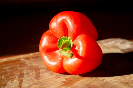 Red pepper on a wooden board. Bright, healthy vegetables. A constrate photo of a bell pepper with a red skin on a wooden board in the dark.の写真素材