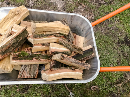 Firewood in a garden wheelbarrow. A lot of chopped wood for heating the house. Firewood for heating the house in winter.の写真素材