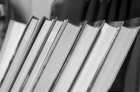 Books are in a row on a shelf. hardcover books. artistic photos of books in black and white. Books of different sizes on the shelf.の写真素材