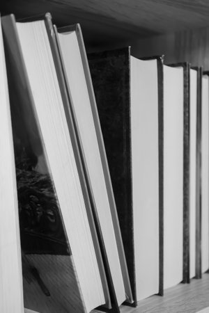 Books are in a row on a shelf. hardcover books. artistic photos of books in black and white. Books of different sizes on the shelf.の写真素材