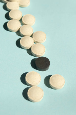pills on a blue background. black and white pills lie interspersed. Bodycare - pills. A handful of pills for health and beauty.の写真素材