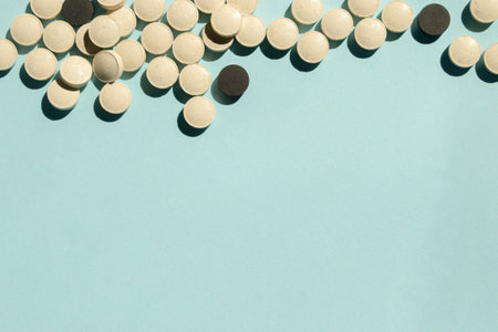 A lot of white and black pills on a blue background. On the blue background on top of the photo collected a lot of colorful tablets. a handful of pills.の写真素材