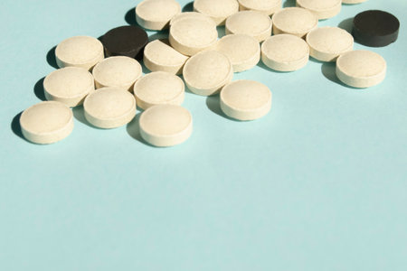 A lot of white and black pills on a blue background. On the blue background on top of the photo collected a lot of colorful tablets. a handful of pills.の写真素材